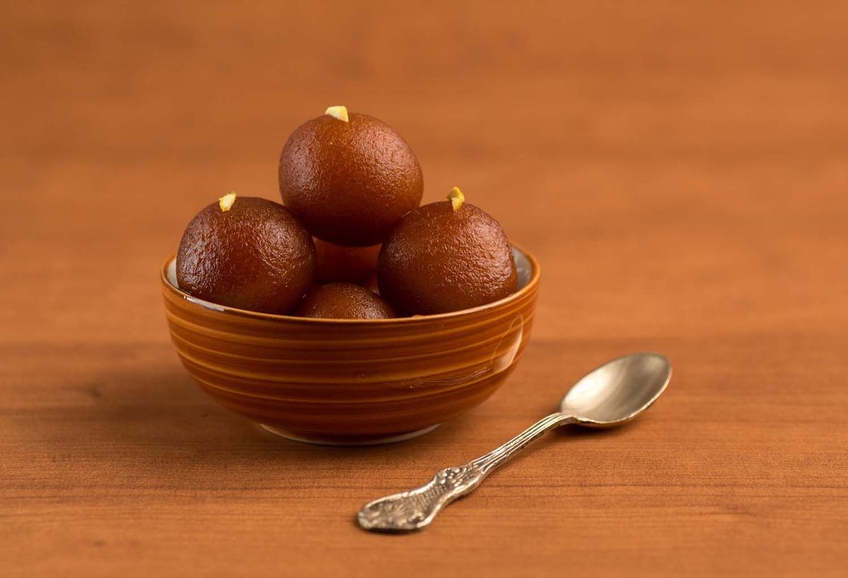 Sweet and delicious Gulab jamun in bowl with a spoon